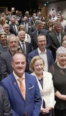 Large group of politicians standing and smiling in conference room